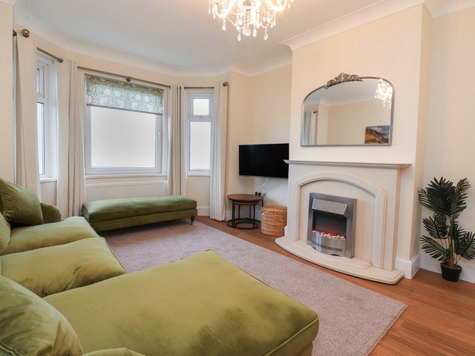 A living room with a green sofa and television at Marilyn in Morecambe