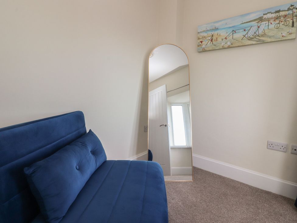 A bedroom with a blue sofa and a mirror at Marilyn in Morecambe