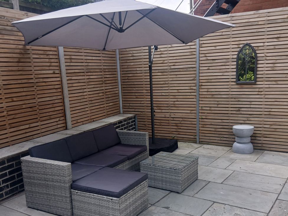 A seating area with a sofa, table, and umbrella at Marilyn in Morecambe