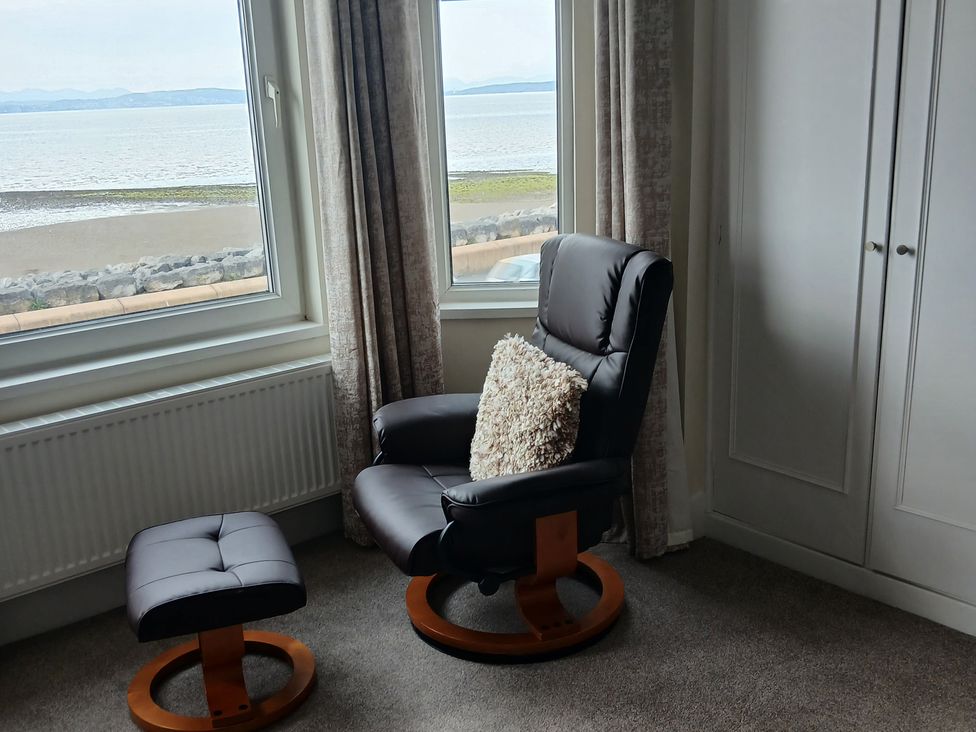 A living room with a chair and footrest near a window at Marilyn in Morecambe