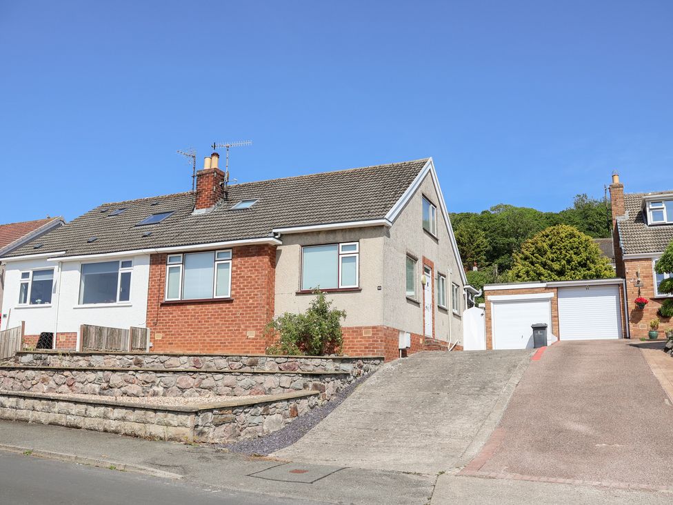 A house with a garage and driveway at Bryn Bach in Rhos-On-Sea