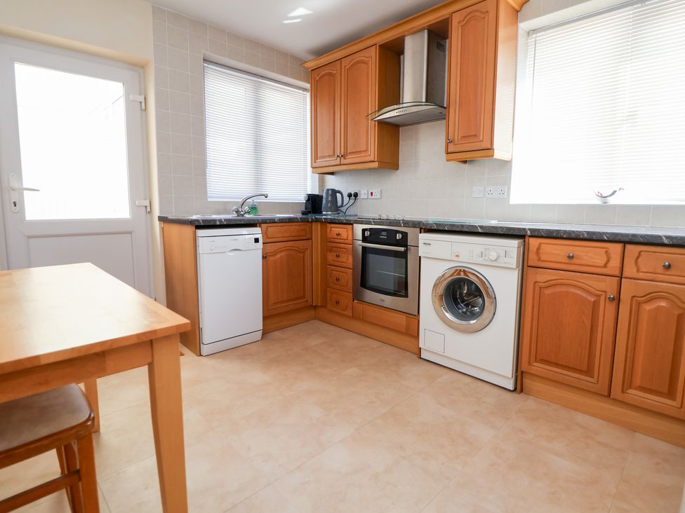 A kitchen with appliances and a table at Bryn Bach in Rhos-On-Sea