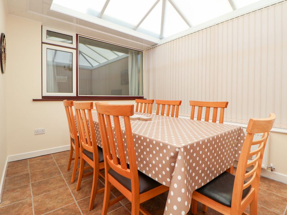 A sunroom with a table and chairs at Bryn Bach in Rhos-On-Sea