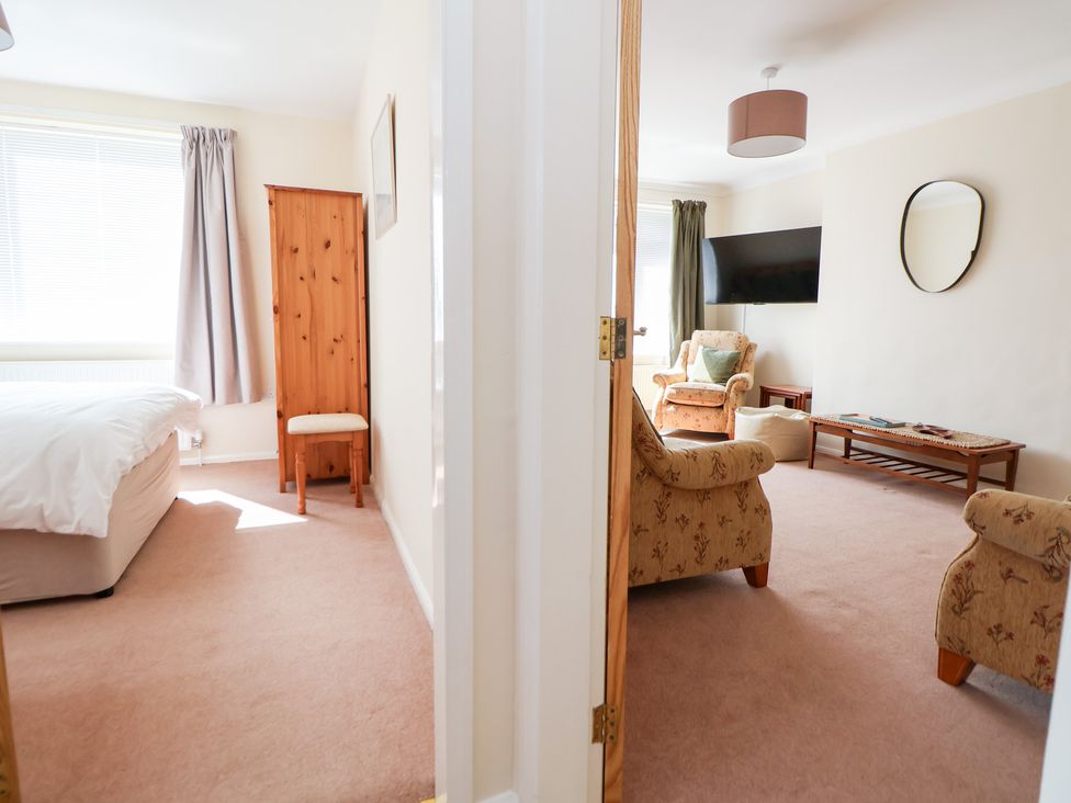 A living room with an armchair and table visible from a doorway at Bryn Bach Rhos-On-Sea