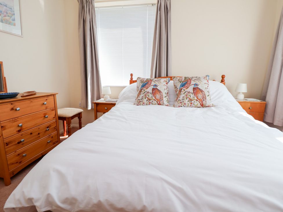 A bedroom with a bed and nightstand at Bryn Bach in Rhos-On-Sea
