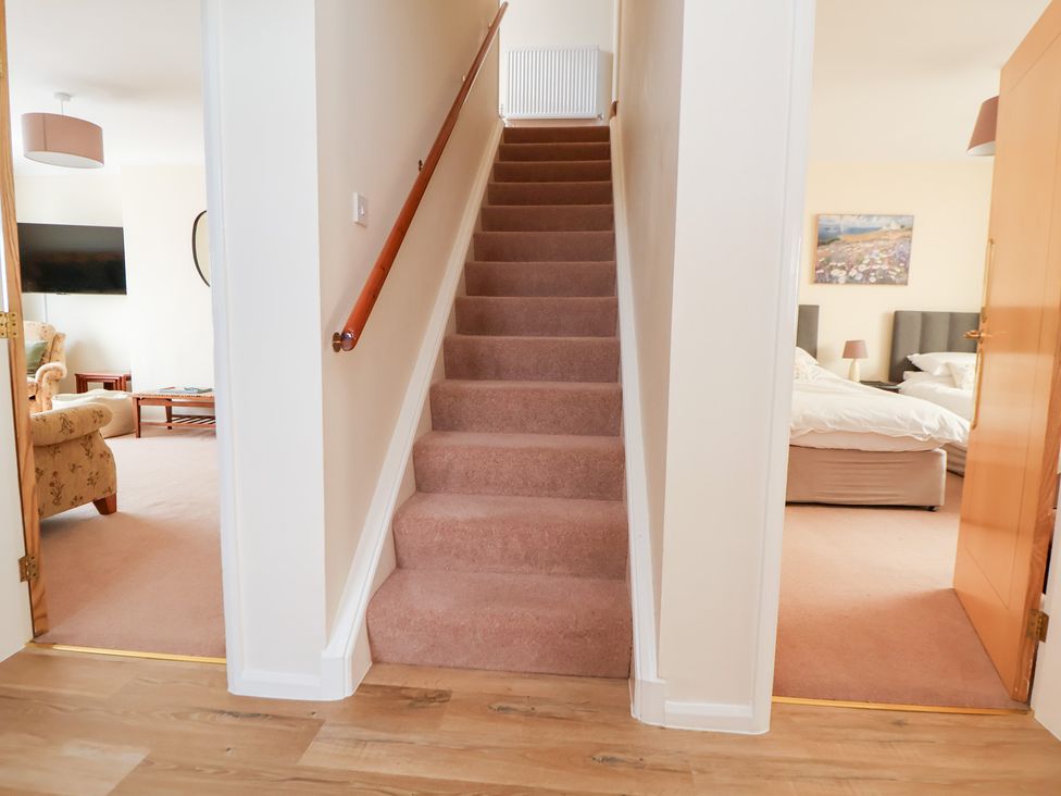A hallway with a staircase and doorways at Bryn Bach in Rhos-On-Sea