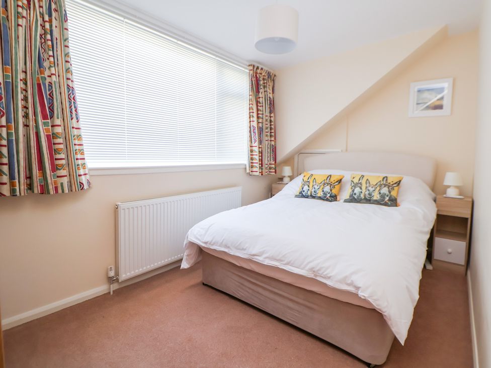 A bedroom with a bed and curtains at Bryn Bach in Rhos-On-Sea