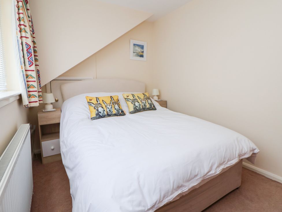 A bedroom with a bed and nightstand at Bryn Bach in Rhos-On-Sea