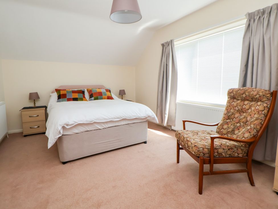 A bedroom with a bed and a chair at Bryn Bach in Rhos-On-Sea