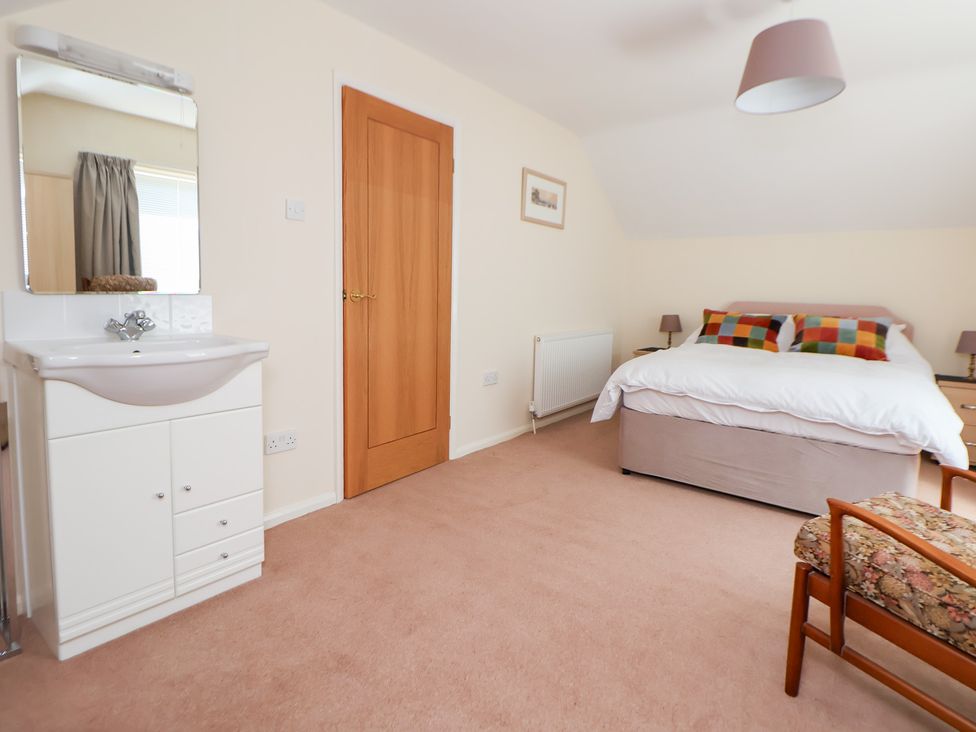 A bedroom with a bed, vanity unit, and chair at Bryn Bach in Rhos-On-Sea