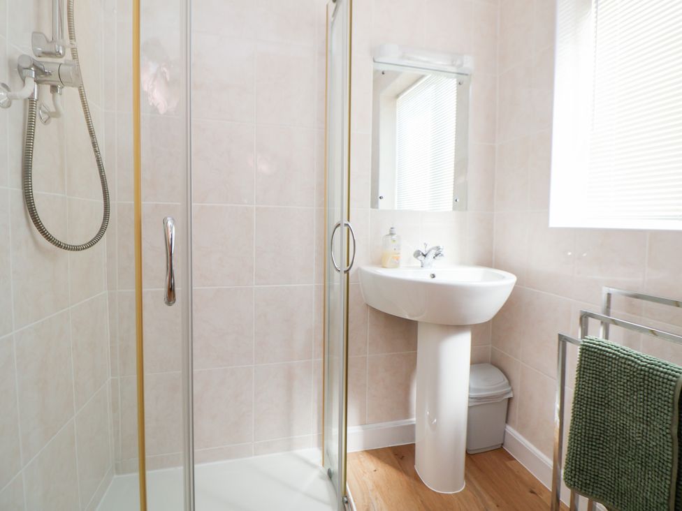 A bathroom with a shower, sink, and mirror at Bryn Bach in Rhos-On-Sea