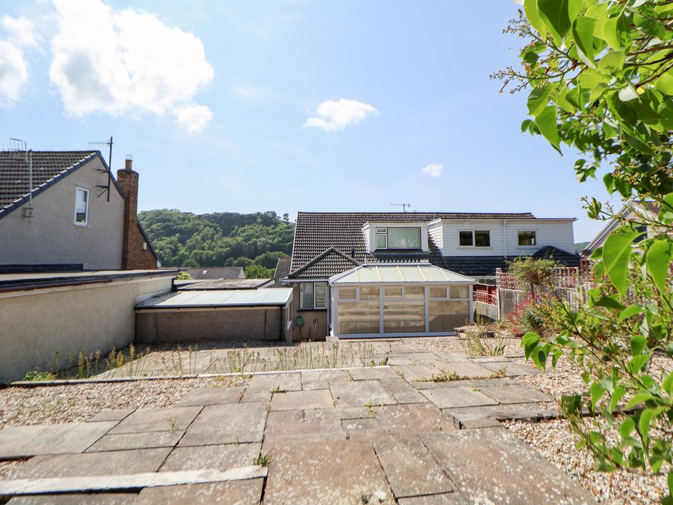 A garden view with a conservatory and houses at Bryn Bach in Rhos-On-Sea