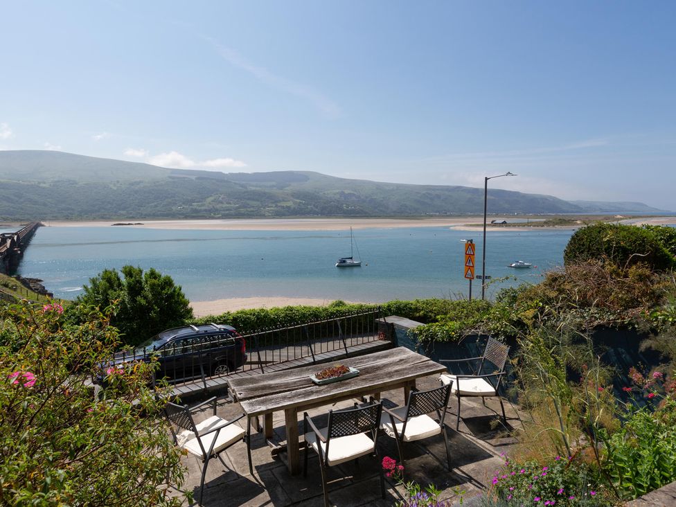An outdoor dining area with a view of the ocean and mountains at Bod Idris in Barmouth