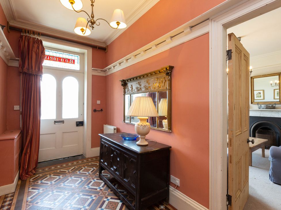 A hallway with a door, a mirror, and a table at Bod Idris in Barmouth