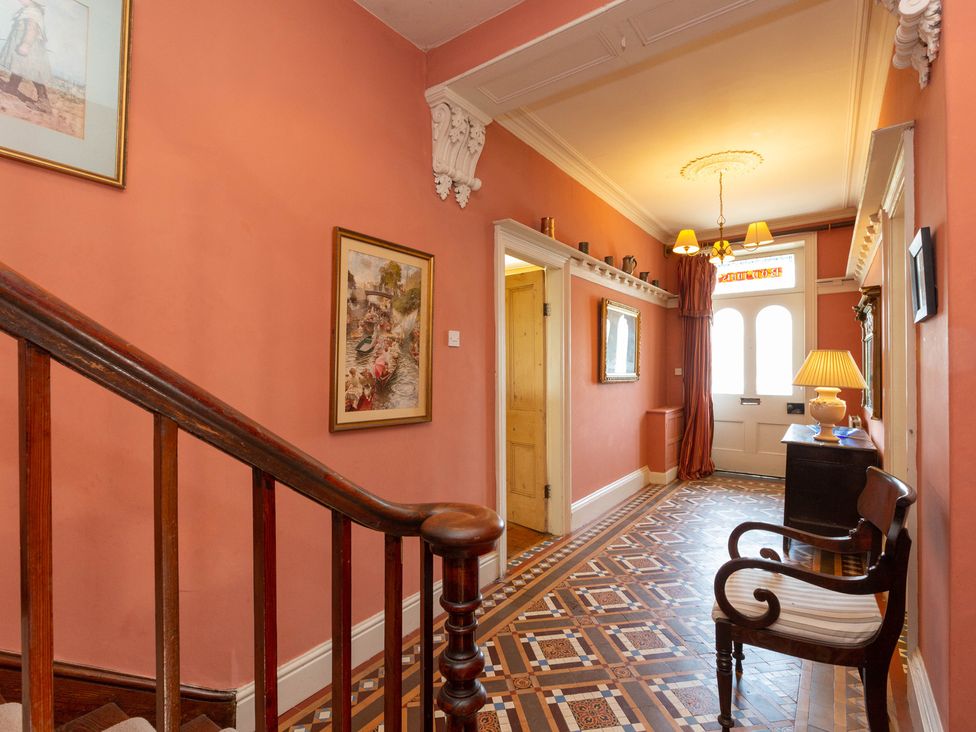 A hallway with paintings on walls and a staircase at Bod Idris in Barmouth