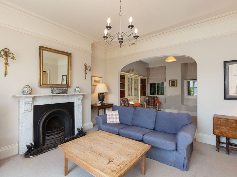 A living room with a sofa, coffee table, and fireplace at Bod Idris in Barmouth