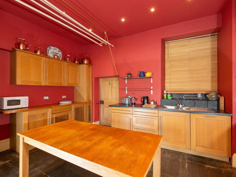 A kitchen with wooden cabinets and a table at Bod Idris in Barmouth