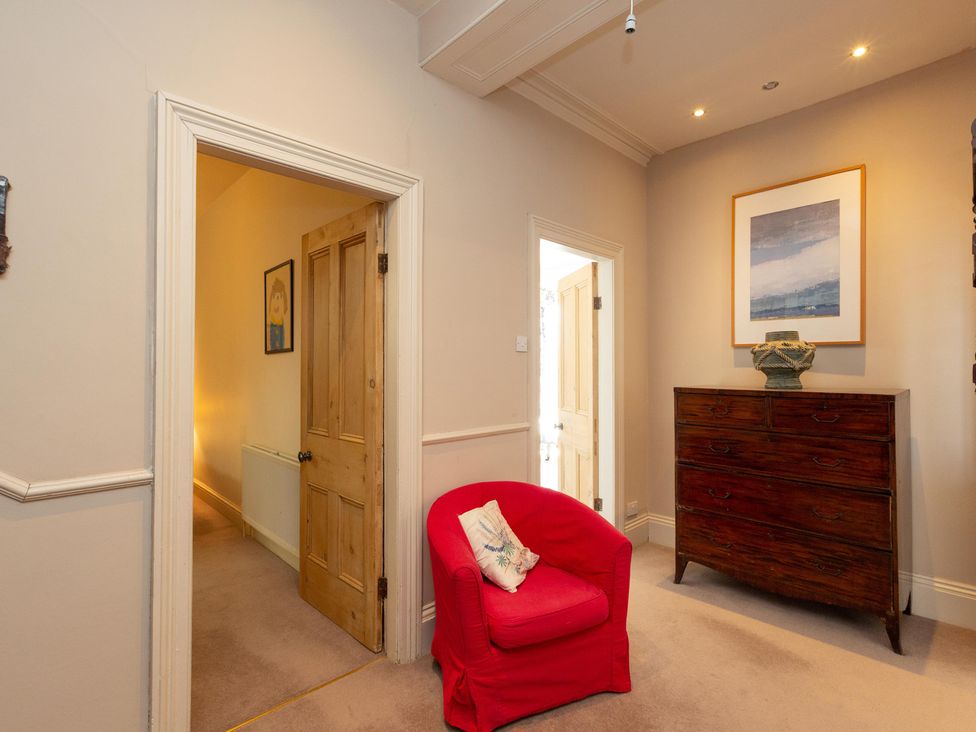 A hallway with a red chair and chest of drawers at Bod Idris in Barmouth