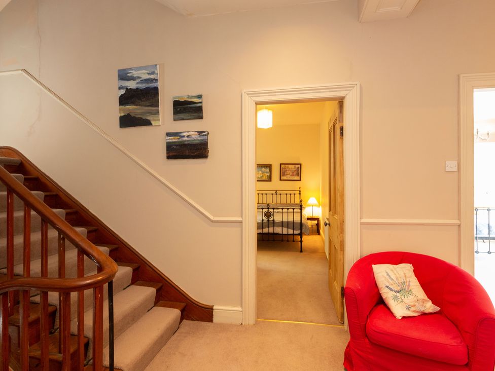 A hallway with stairs and paintings leading to a bedroom at Bod Idris in Barmouth