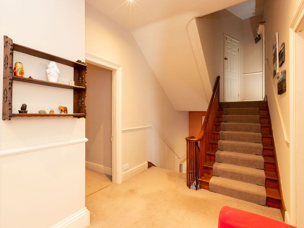 A hallway with stairs and a shelf at Bod Idris in Barmouth