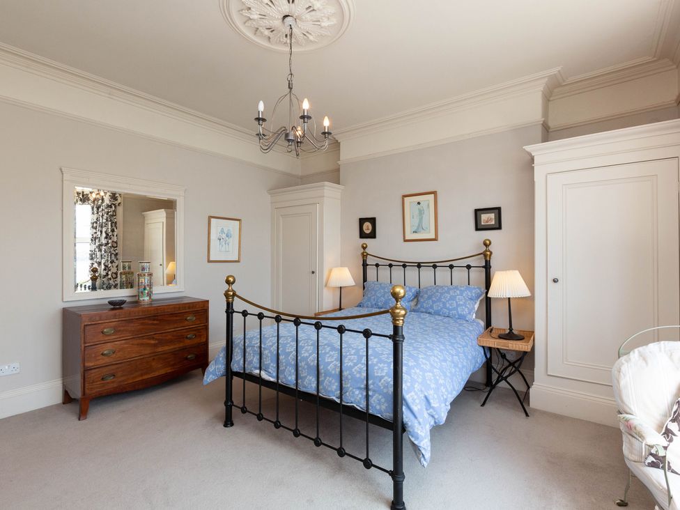 A bedroom with a bed, dresser, and mirror at Bod Idris in Barmouth