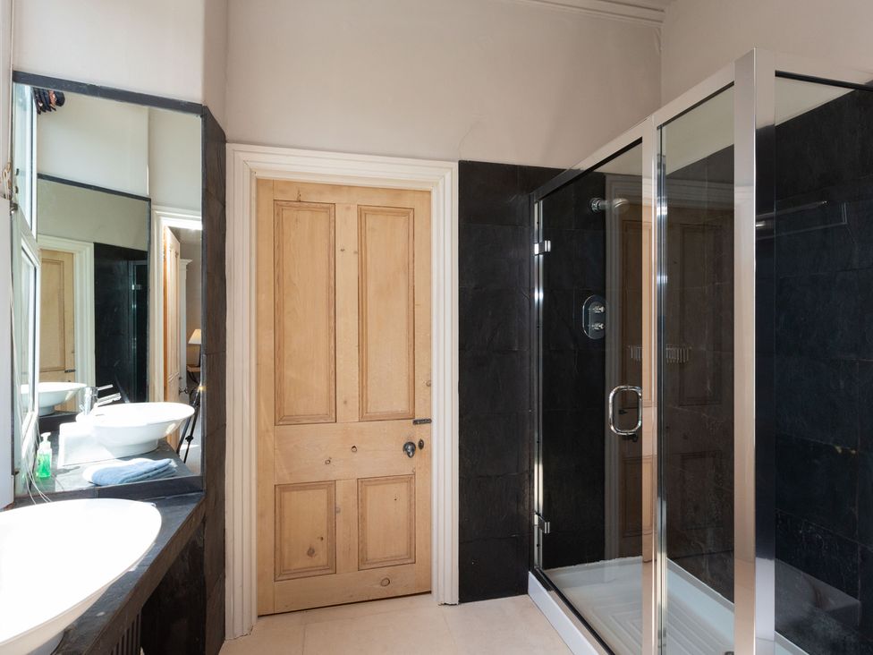 A bathroom featuring a sink, shower, and mirror at Bod Idris in Barmouth