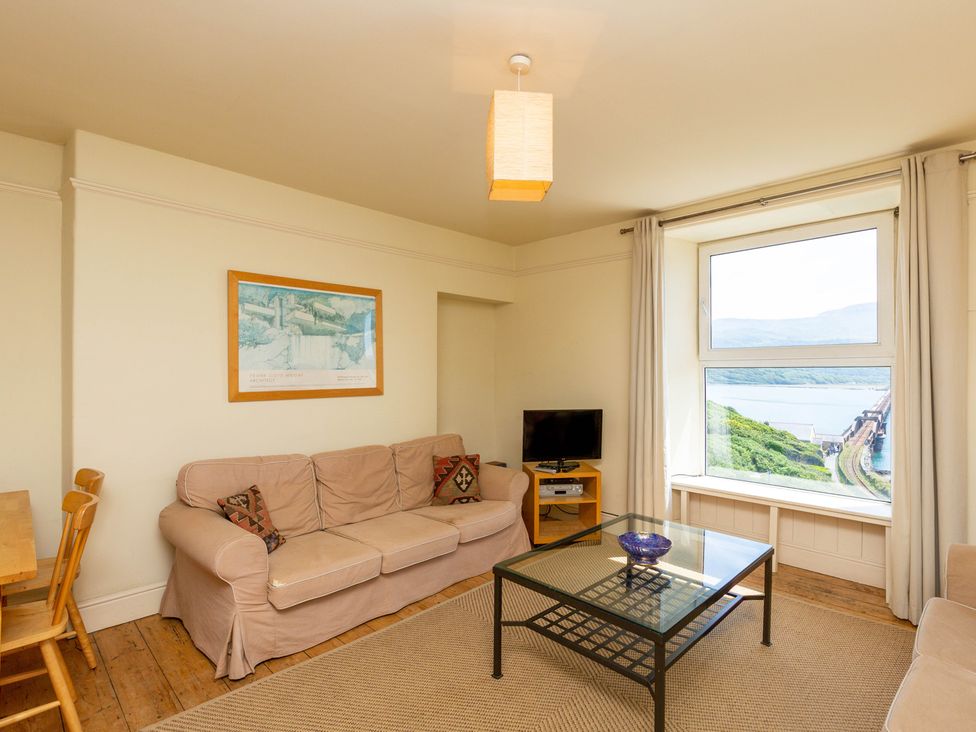 A living room with a sofa, table, and television at Bod Idris in Barmouth