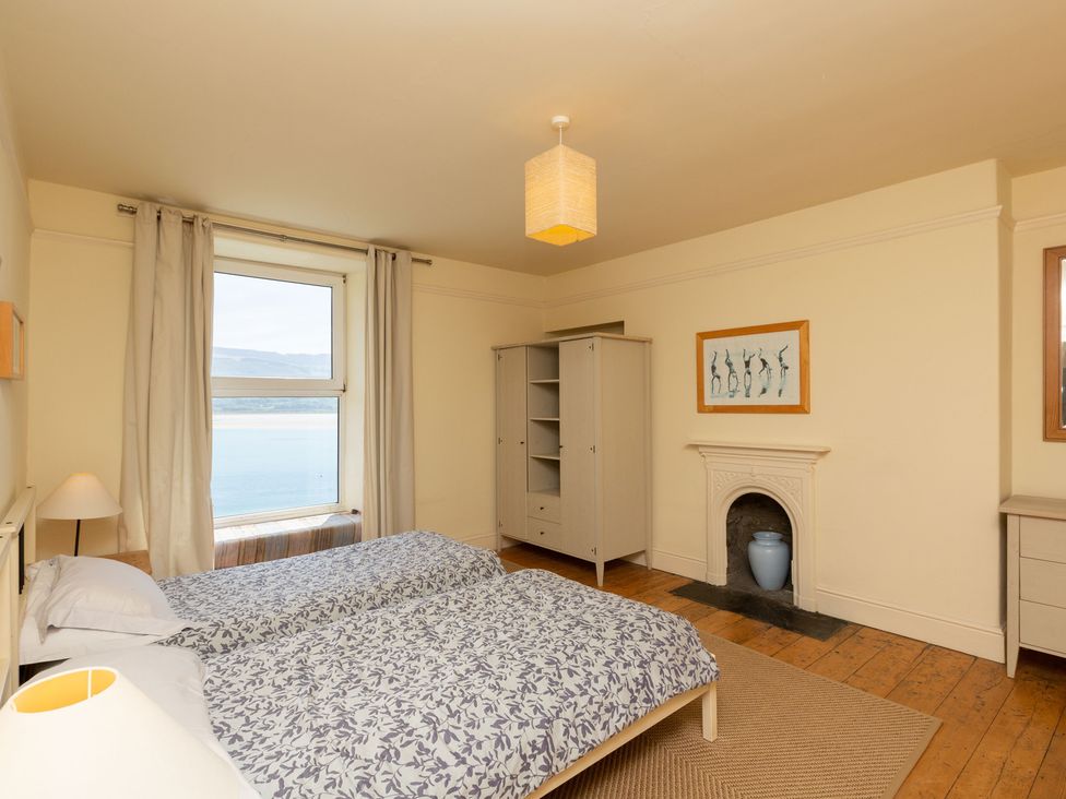 A bedroom with two beds and a wardrobe at Bod Idris in Barmouth