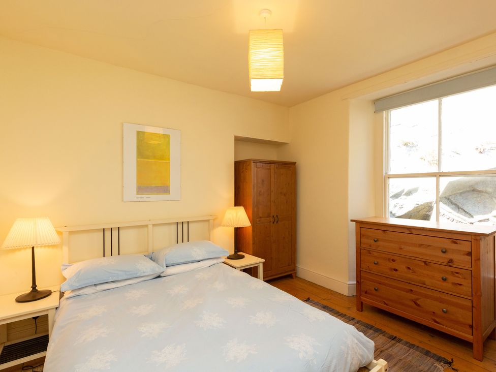 A bedroom with a bed, wardrobe, and drawers at Bod Idris in Barmouth