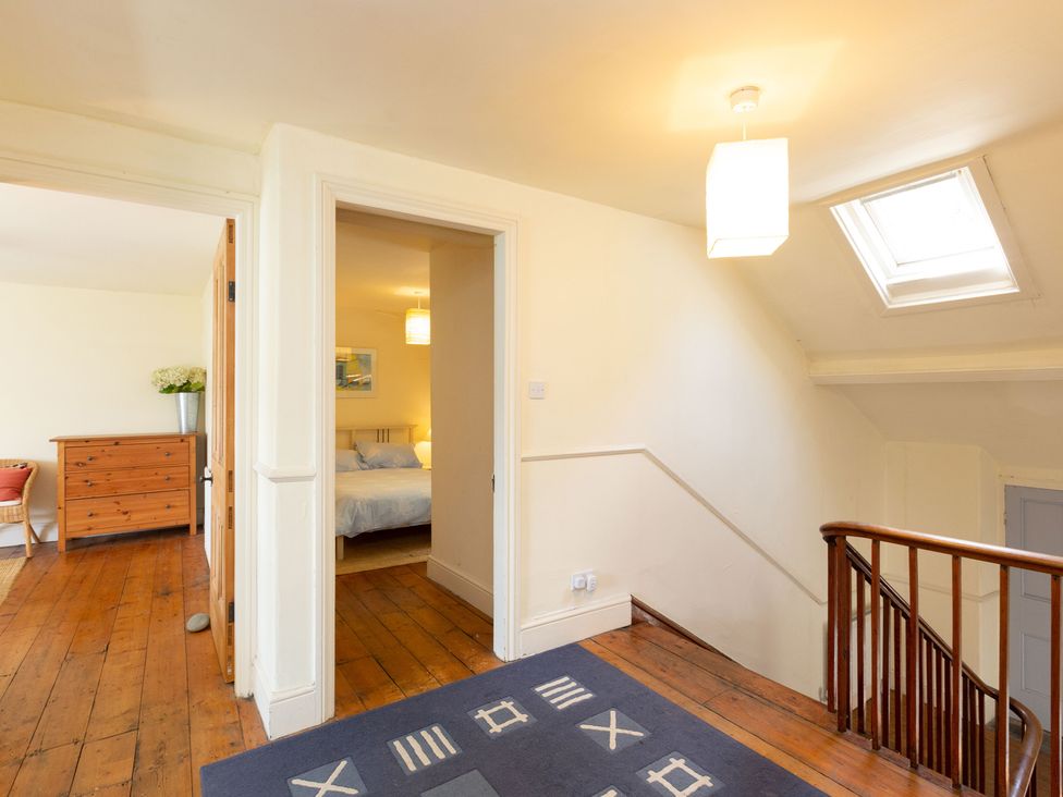 A hallway with a staircase and a chest of drawers at Bod Idris in Barmouth