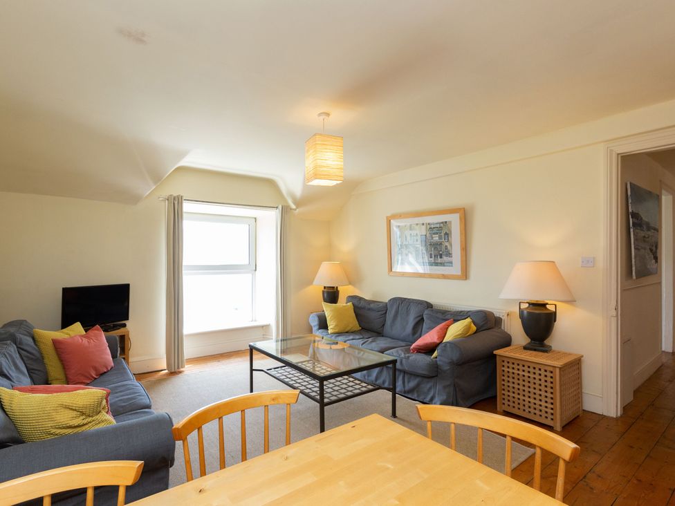 A living room with a sofa, table, and television at Bod Idris in Barmouth