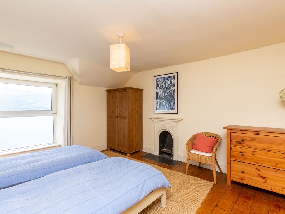 A bedroom with two beds and a wardrobe at Bod Idris in Barmouth