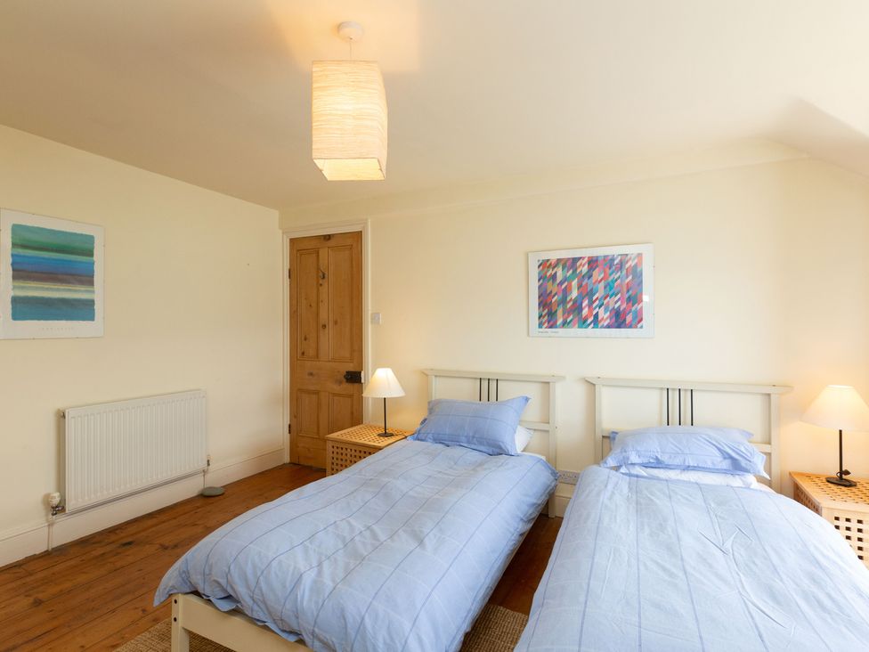 A bedroom with two single beds and a wooden door at Bod Idris in Barmouth