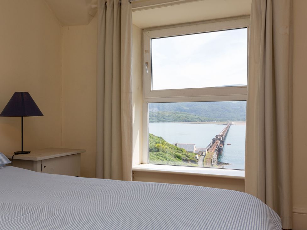 A bedroom with a bed and lamp overlooking a pier at Bod Idris, Barmouth