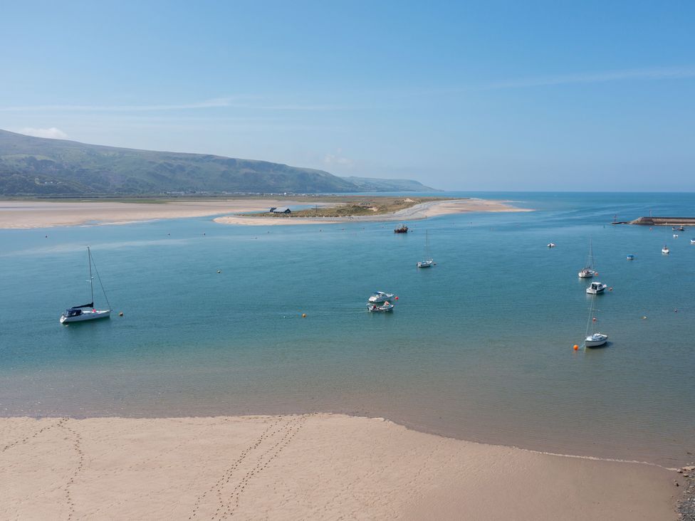 A view of boats in water with a sandy shore and mountains in the background at Bod Idris in Barmouth