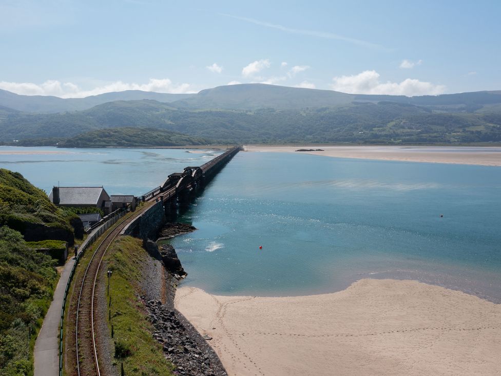 A railway bridge over water with sand and mountains at Bod Idris Barmouth
