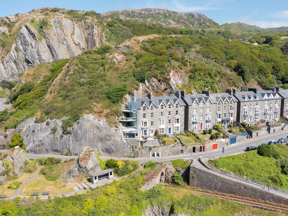 A view of houses along a road beside cliffs at Bod Idris Barmouth