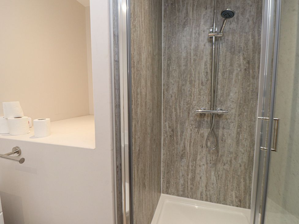 A shower with a showerhead and toilet paper in a bathroom at The Hideaway
