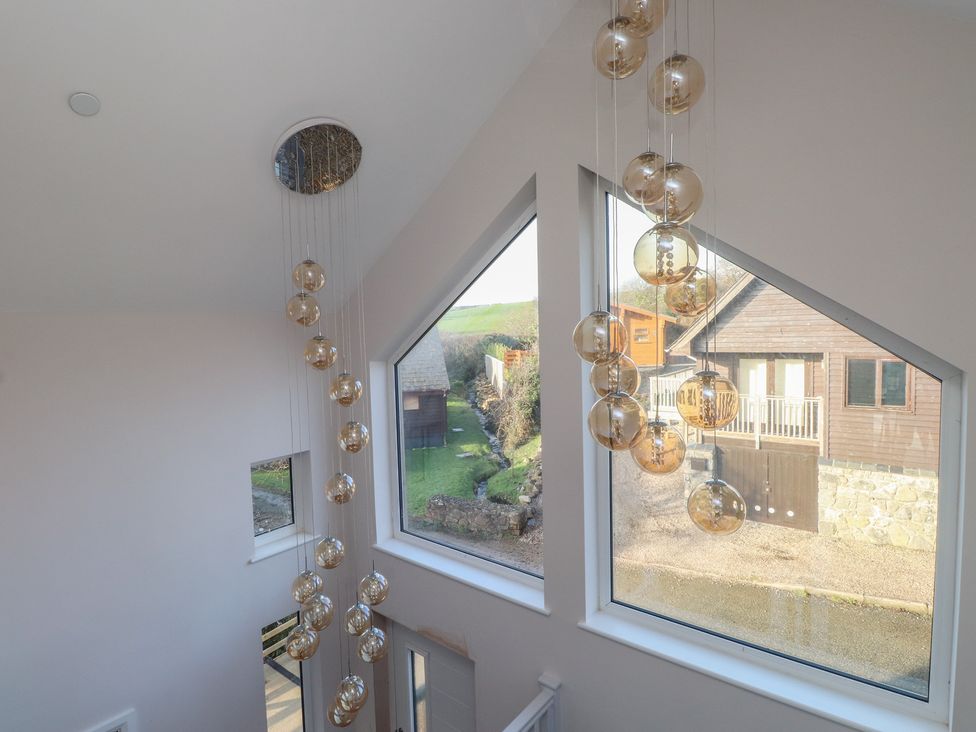 A staircase with a modern light fixture and large windows at The Hideaway