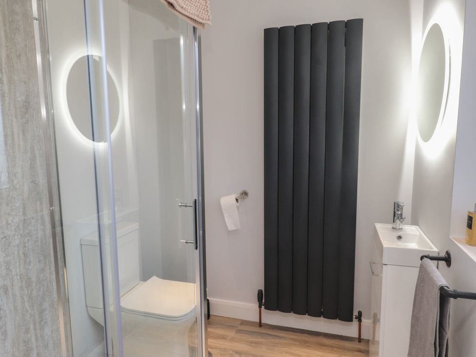 A bathroom with a shower, toilet, and sink at The Hideaway