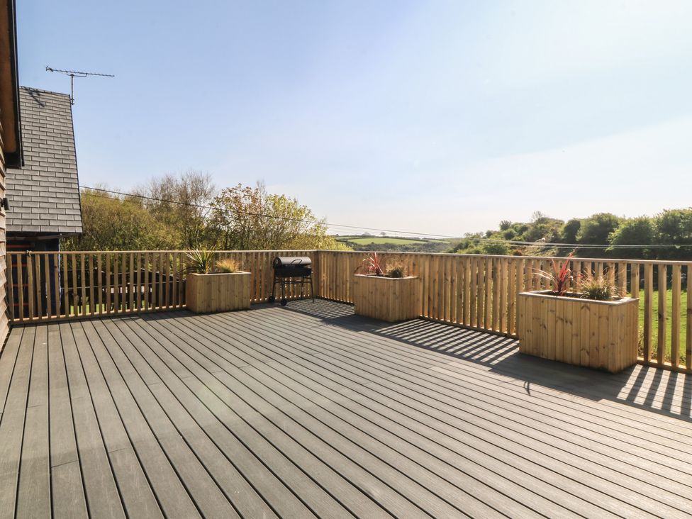 An outdoor deck with planters and a grill at The Hideaway in Mynytho near Abersoch