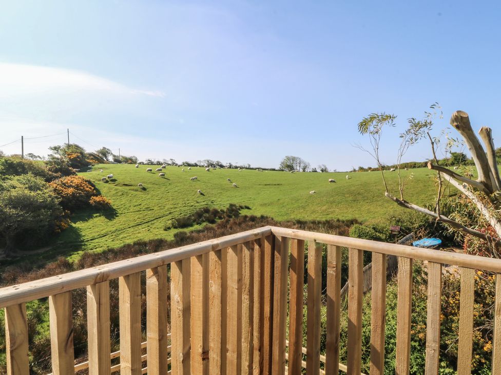 A view of sheep on grassland from a balcony at The Hideaway in Mynytho near Abersoch