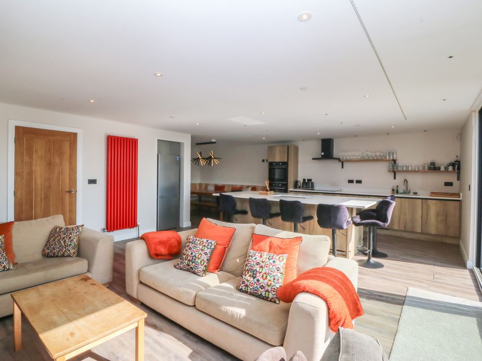 A living room with a sofa and kitchen area at The Hideaway Mynytho near Abersoch