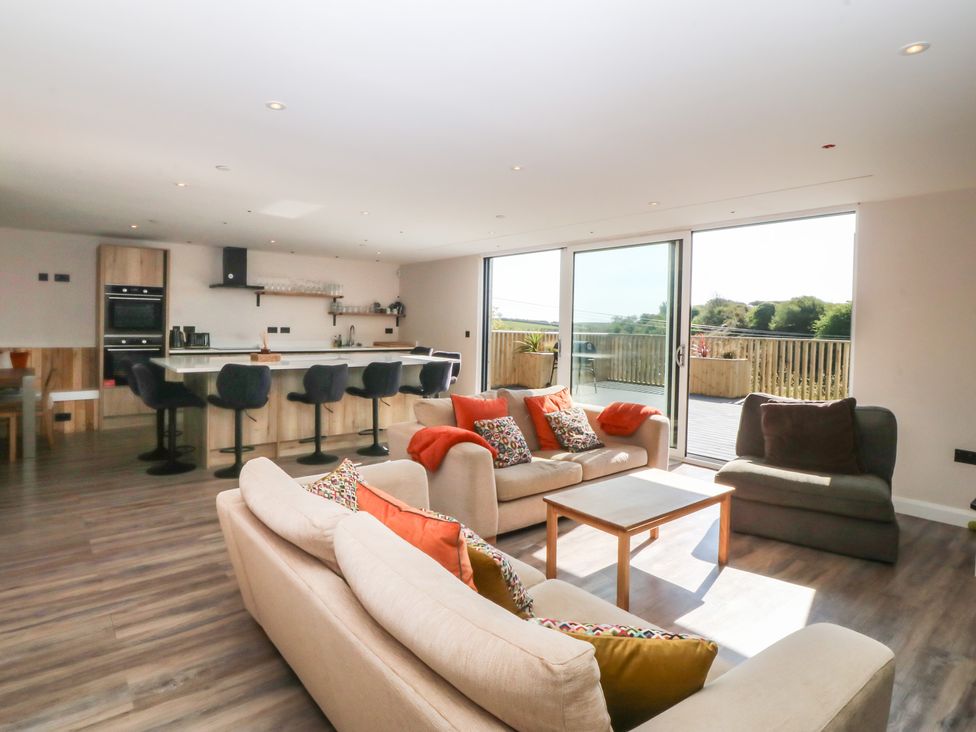 A living room with sofas and a kitchen area at The Hideaway in Mynytho near Abersoch