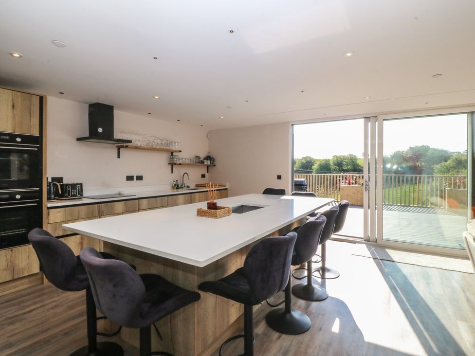A kitchen with an island and bar stools at The Hideaway in Mynytho near Abersoch