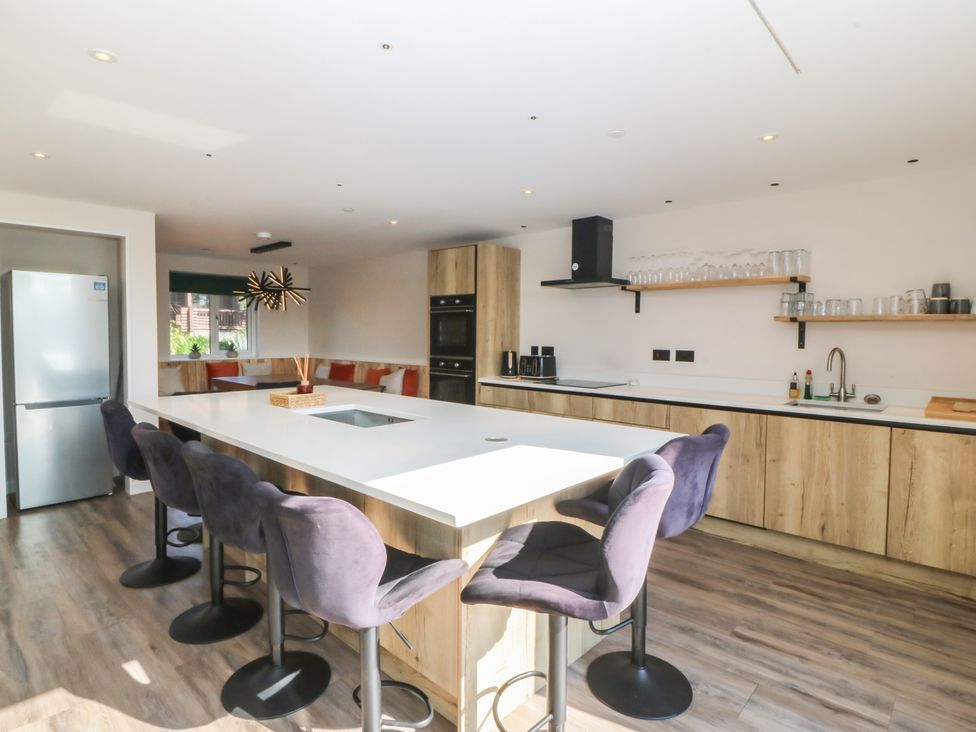 A kitchen with a counter, bar stools, refrigerator, and oven at The Hideaway in Mynytho near Abersoch
