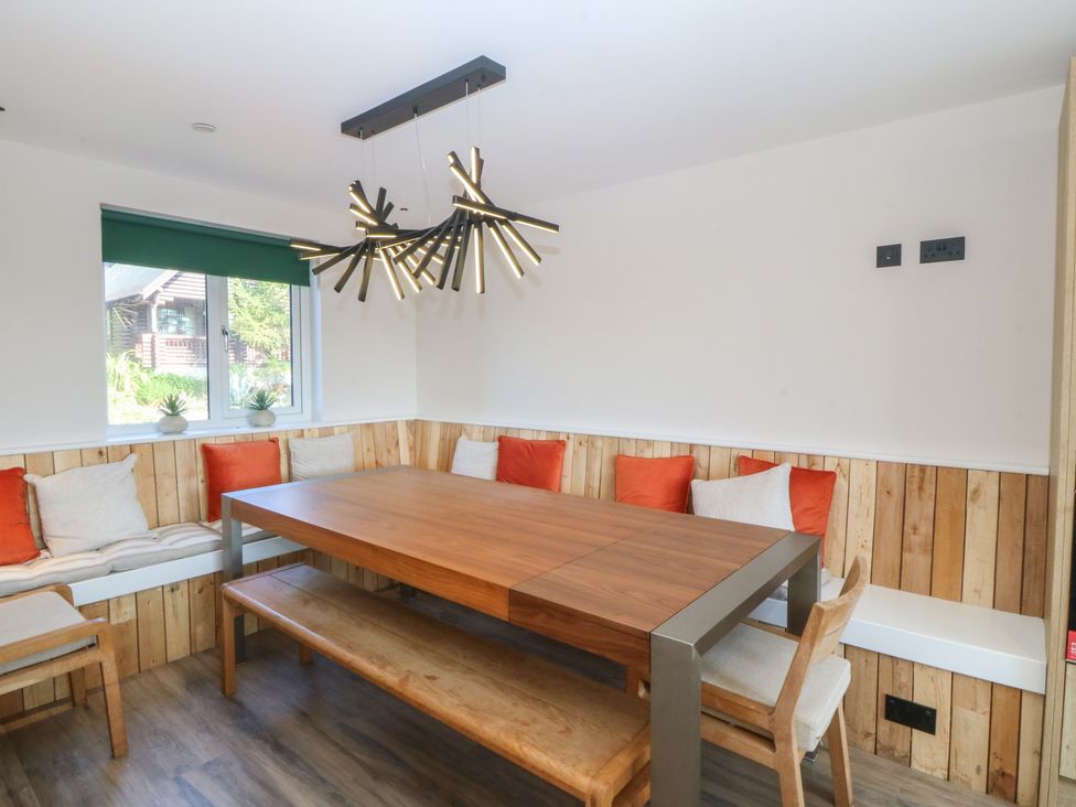 A dining room with a wooden table and benches at The Hideaway in Mynytho near Abersoch