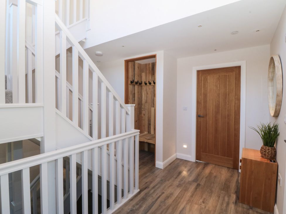 A hallway with a staircase and a bench with coat hooks at The Hideaway in Mynytho near Abersoch