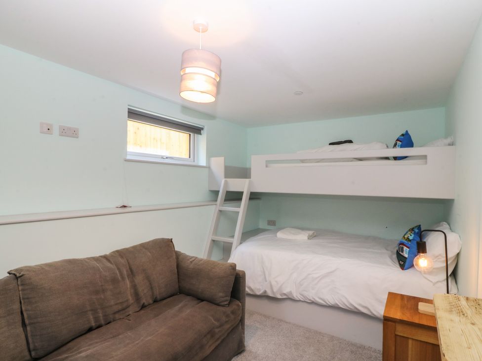 A bedroom with a bunk bed and a sofa at The Hideaway in Mynytho near Abersoch