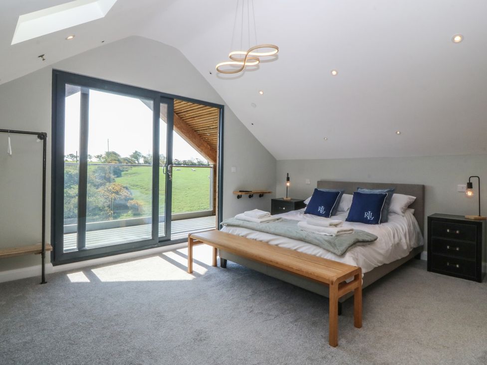 A bedroom with a bed, bedside table, and sliding doors at The Hideaway in Mynytho near Abersoch